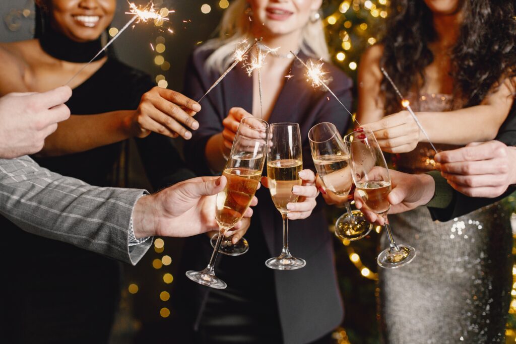 midsection people holding glasses with champagne while celebrating new year