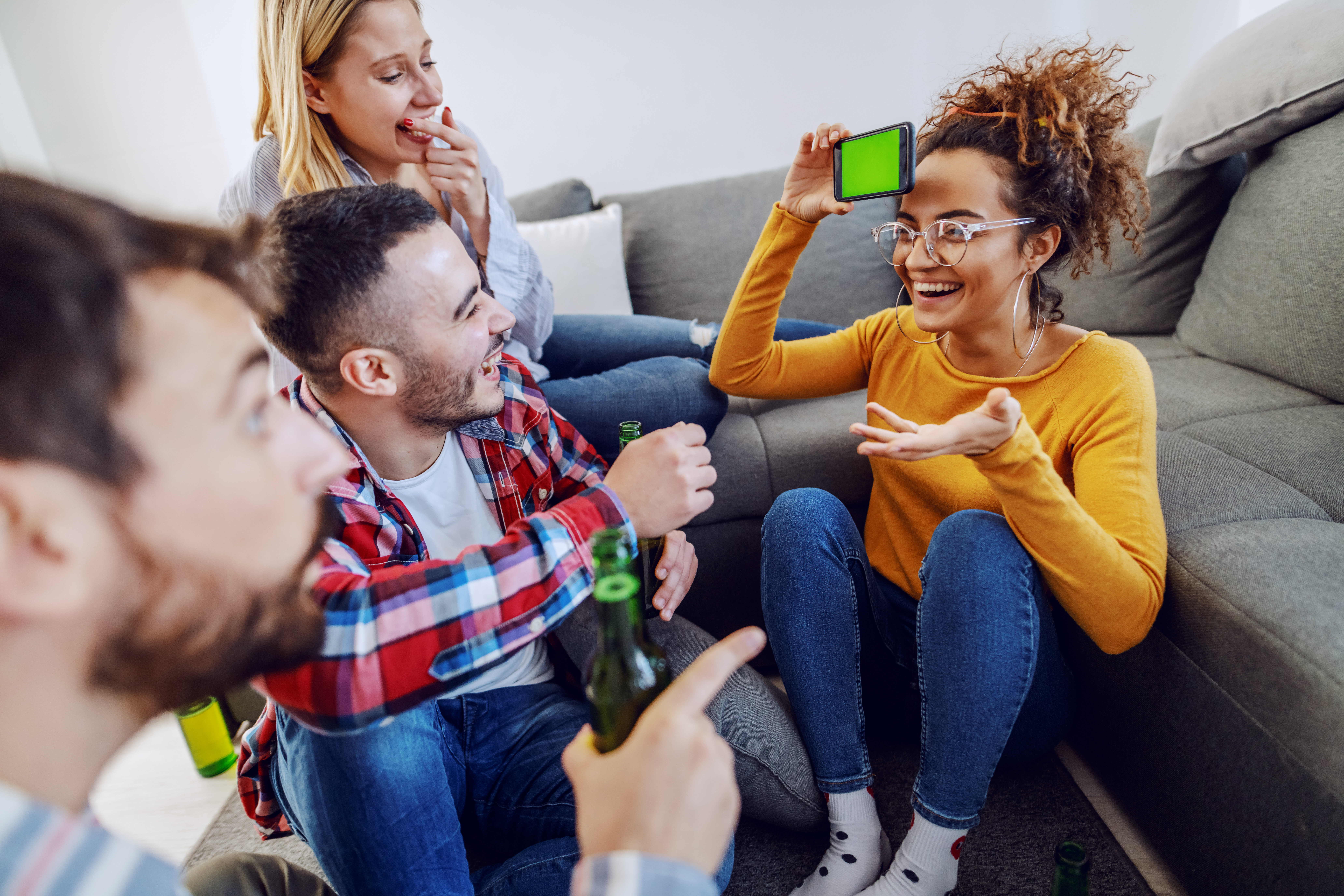 group cheerful playful friends playing charades with smart phone home interior